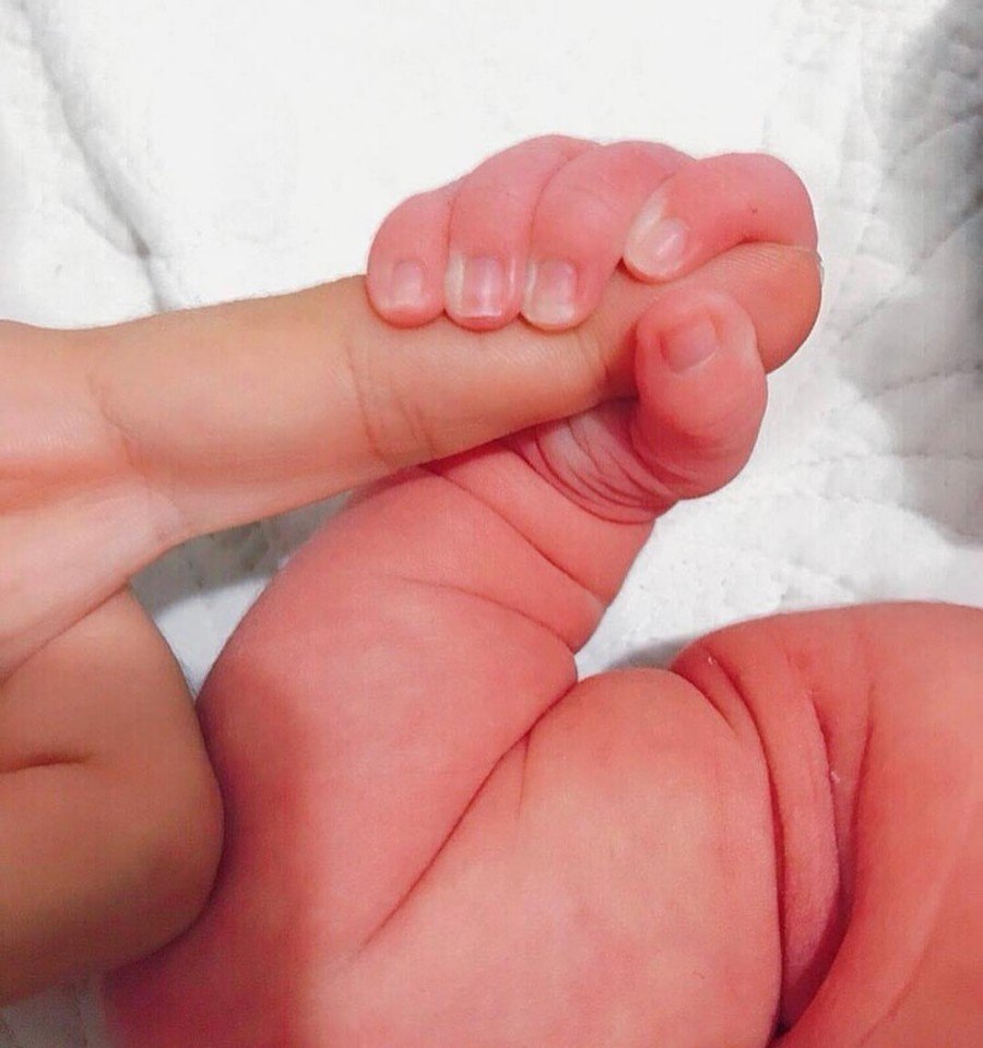 Младенец держит мамин пальчик