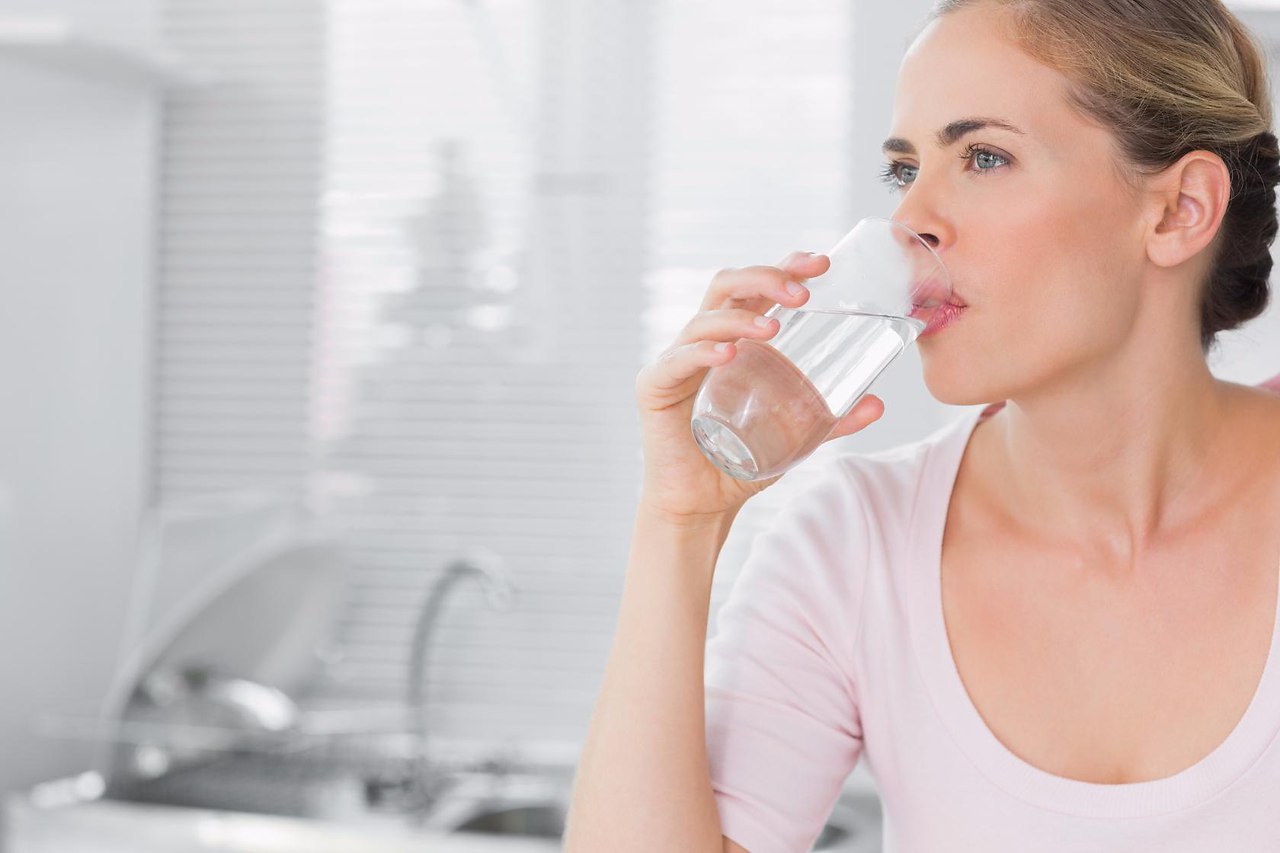 Тошнота утром на голодный желудок у женщин. Женщина пьет воду. Женщина со стаканом воды. Девушка пьет из стакана. Питье воды.